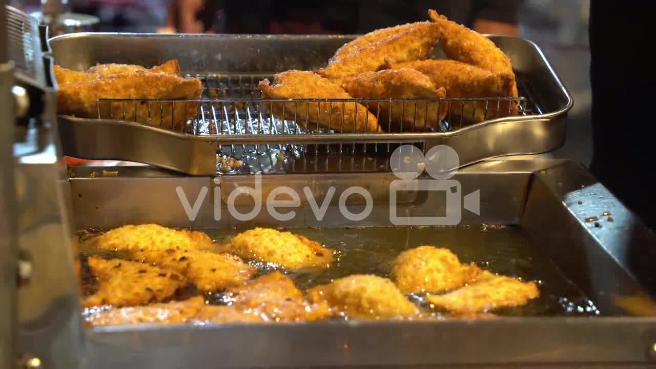 Deep frying in hot oil, cooking in progress of tasty jiucai hezi, fried chinese leek dumplings stuff