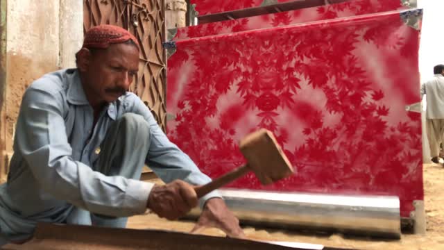 a man hammering a iron sheets