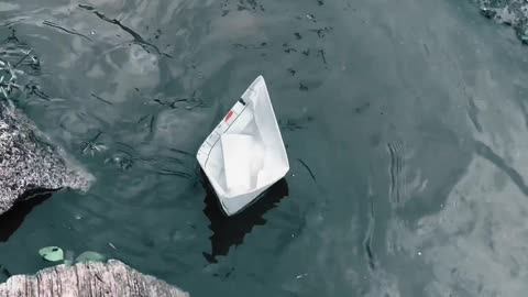 A Paper Boat Floating Over A Roadside Water Canal