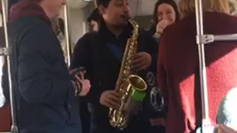 Guy playing saxophone on subway train