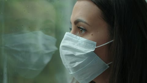 woman-with-mask looking at rain-through window 2021