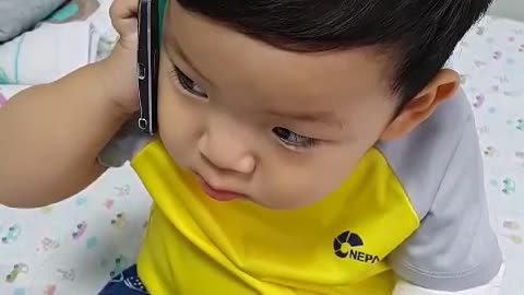 This is a video of a baby pretending to be talking on a cell phone.