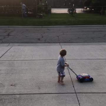 Little Boy Imitates Older Neighbor As He Mows His Lawn