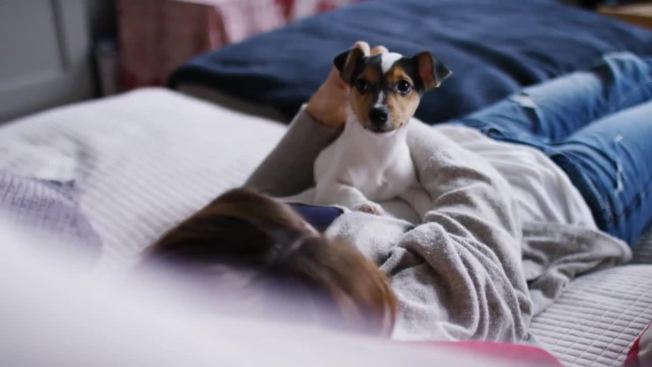 Young woman cuddles and strokes her puppy on her chest as she relaxes, in slow motion