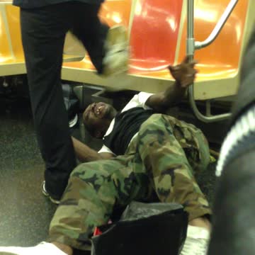 Two men wrestle on the floor with each other on subway train