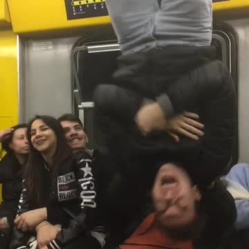 Guy black jacket hangs upside down subway train