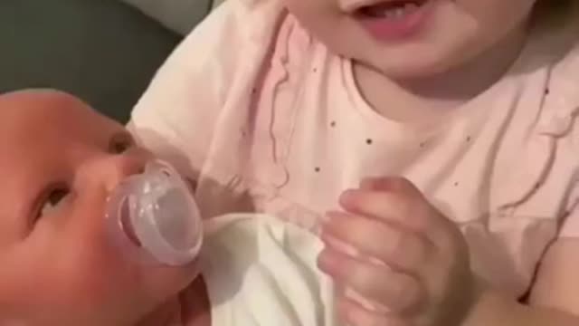 Cute girl making her baby brother to sleep