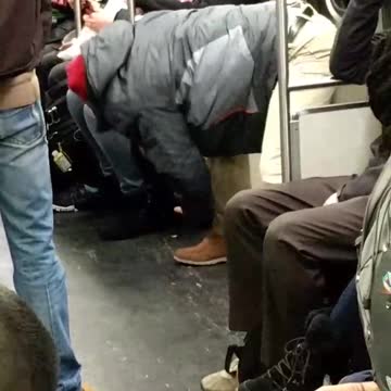 Guy in khaki pants and timbs stretching in subway