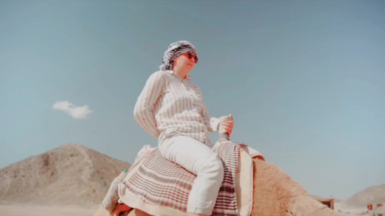 A girl leads passengers on a camel in an empty desert