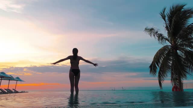 Woman doing yoga in a pool at sunset