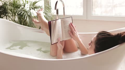 Woman Reading a Book while Lying Down in a Bathtub