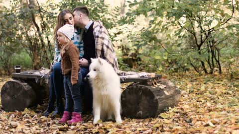 Happy couple sitting and talking with white samoyed dog in the park