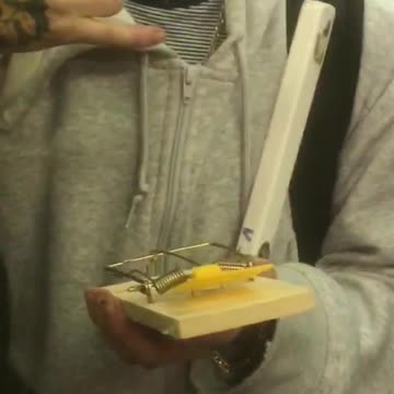 Man with blond hair has rat trap in hand on train