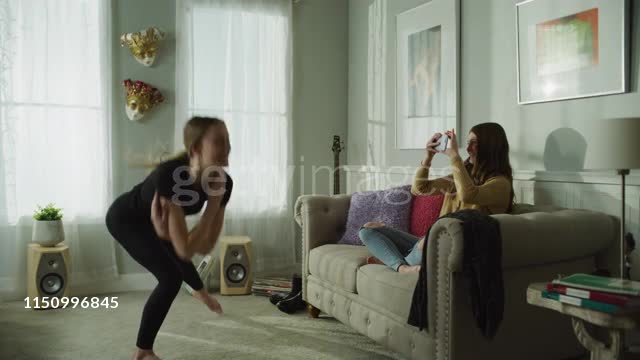 Girl with cell phone recording sister dancing in livingroom / Cedar Hills, Utah, United States