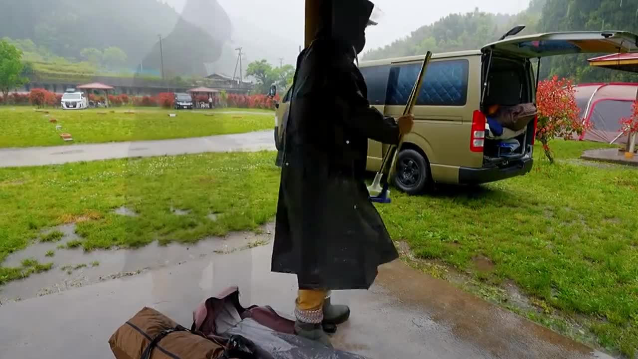 A family with three people camping in the rain
