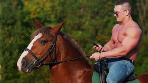 Young man weightlifter sitting on a beautiful horse