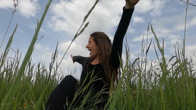 A Woman Playing With Her Dog While Sitting On The Grass