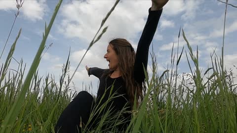 A Woman Playing With Her Dog While Sitting On The Grass