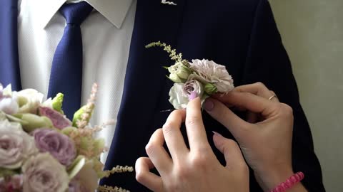 the girl adjusts the flower on the groom's jacket