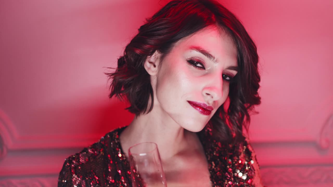 A Woman In A Gold Dress Having A Sip Of Alcoholic Drink While Posing In A photo Shoot
