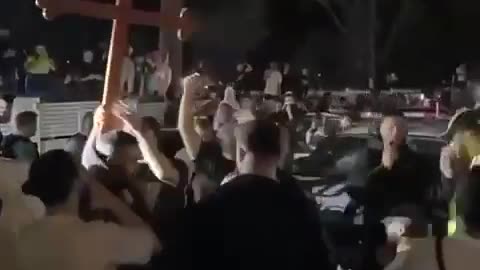 Christians in Australia hold up a cross outside the jail where a terrorist is being