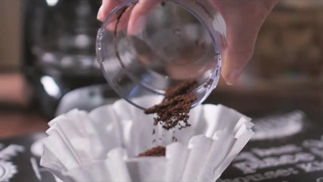 Coffee powder being poured on the coffee maker filter