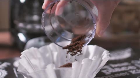 Coffee powder being poured on the coffee maker filter