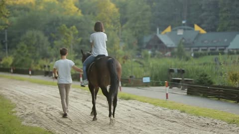Young couple having fun on weekends. A girl riding a horse with her boyfriend
