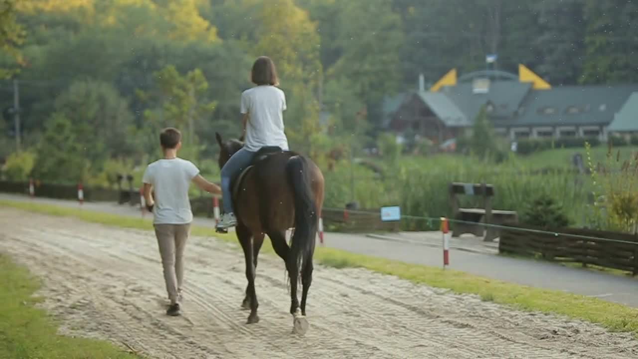 Young couple having fun on weekends. A girl riding a horse with her boyfriend