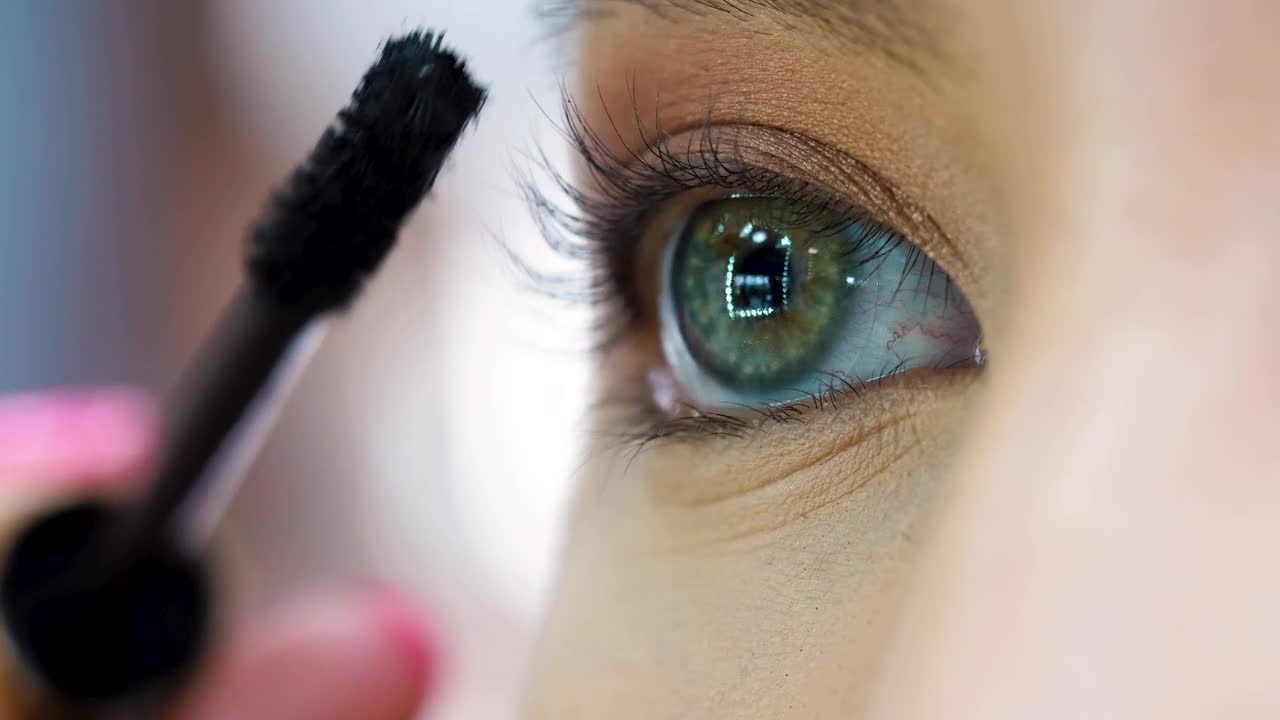 Woman applying mascara in her eyes