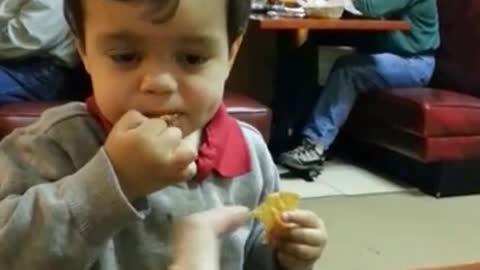 Little boy attempts to drink hot sauce through a straw.