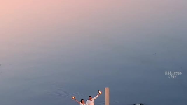 A newlywed couple is having a wedding by the lake at night