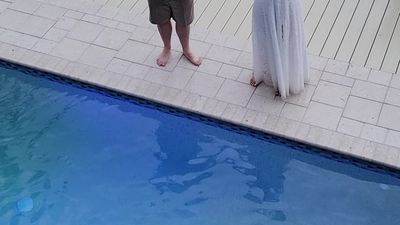 Bride and groom jump in pool