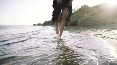 Puppy running near it owner legs in pebble beach during sunset