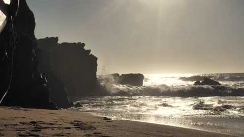 Surfer walking toward the ocean at sunset