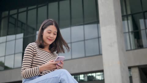 Young beauty girl smiling while playing with her phone