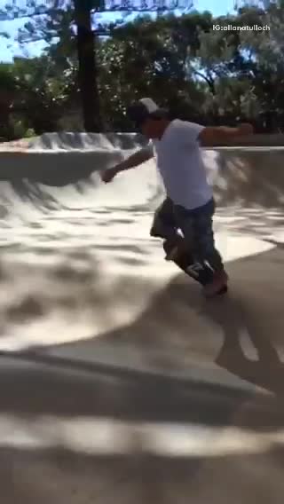 Barefoot guy with white shirt skateboards on ramp and falls off board