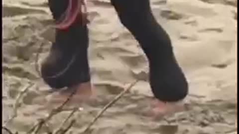 Wetsuit guy carries blue surfboard up sand hill