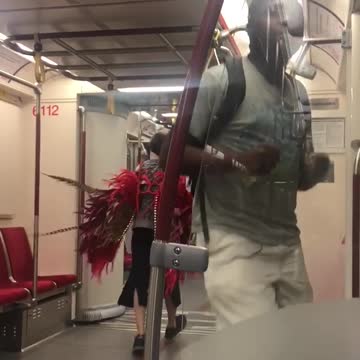Guy rapping lady in grey with red feather wings dancing moving towards him