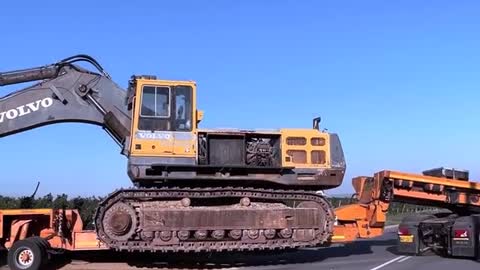 Transporting and uploading volvo big excavator on huge hopper trailor