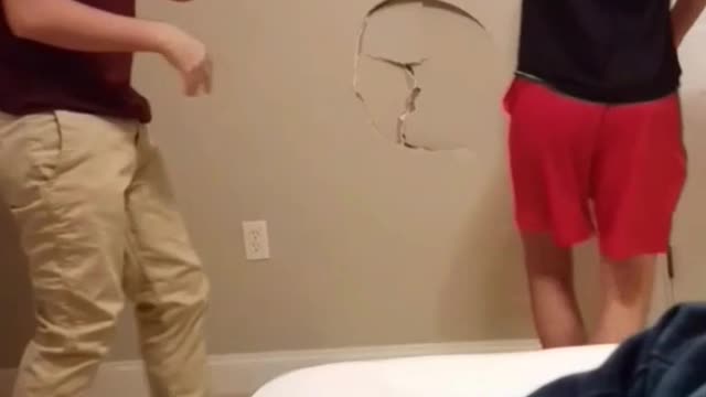 Two guys play wrestling they make a hole in the wall