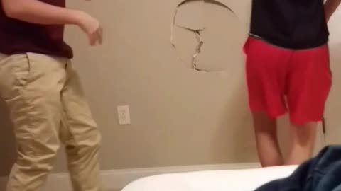 Two guys play wrestling they make a hole in the wall