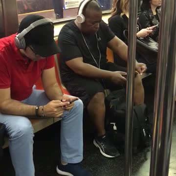 Guy white headphones dancing on subway seat black clothes