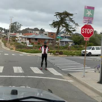 Guy skiing on streets with rollerblades red white black jacket