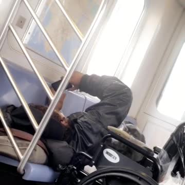 Guy laying down on seat next to wheelchair watching phone