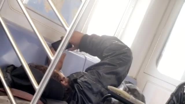 Guy laying down on seat next to wheelchair watching phone