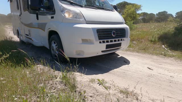 A Camper Van Driving on an Unpaved Road