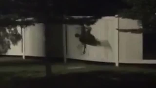 Black clothing throws self through white fence