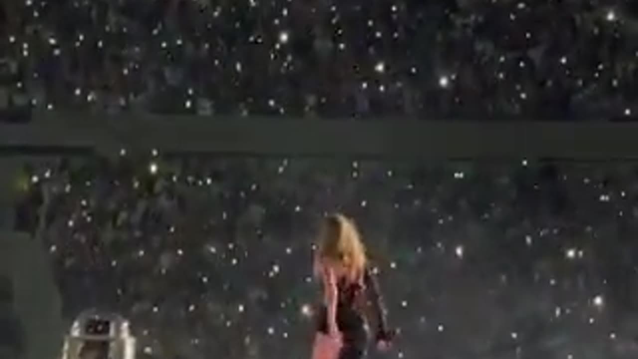 Taylor Swift singing on a black cube.