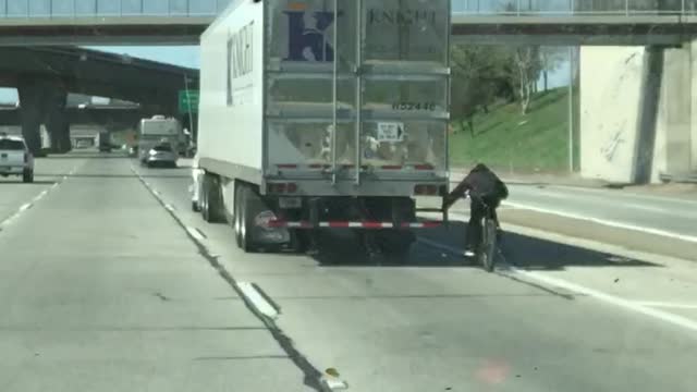 Cyclist Hitches Ride on Semi Truck on Highway